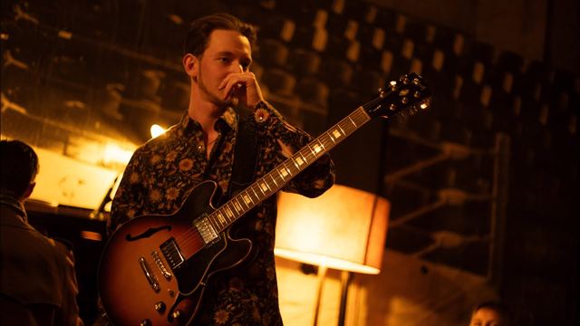 Video still: Jure Slapar with his guitar on a dimly lit stage in Ljubljana